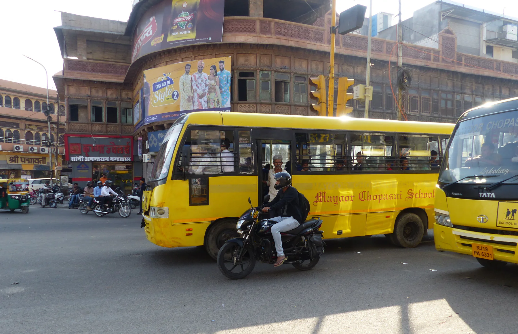 Buses, motorcycles and an auto-rickshaw moving through a Jodhpur crossing in 2018